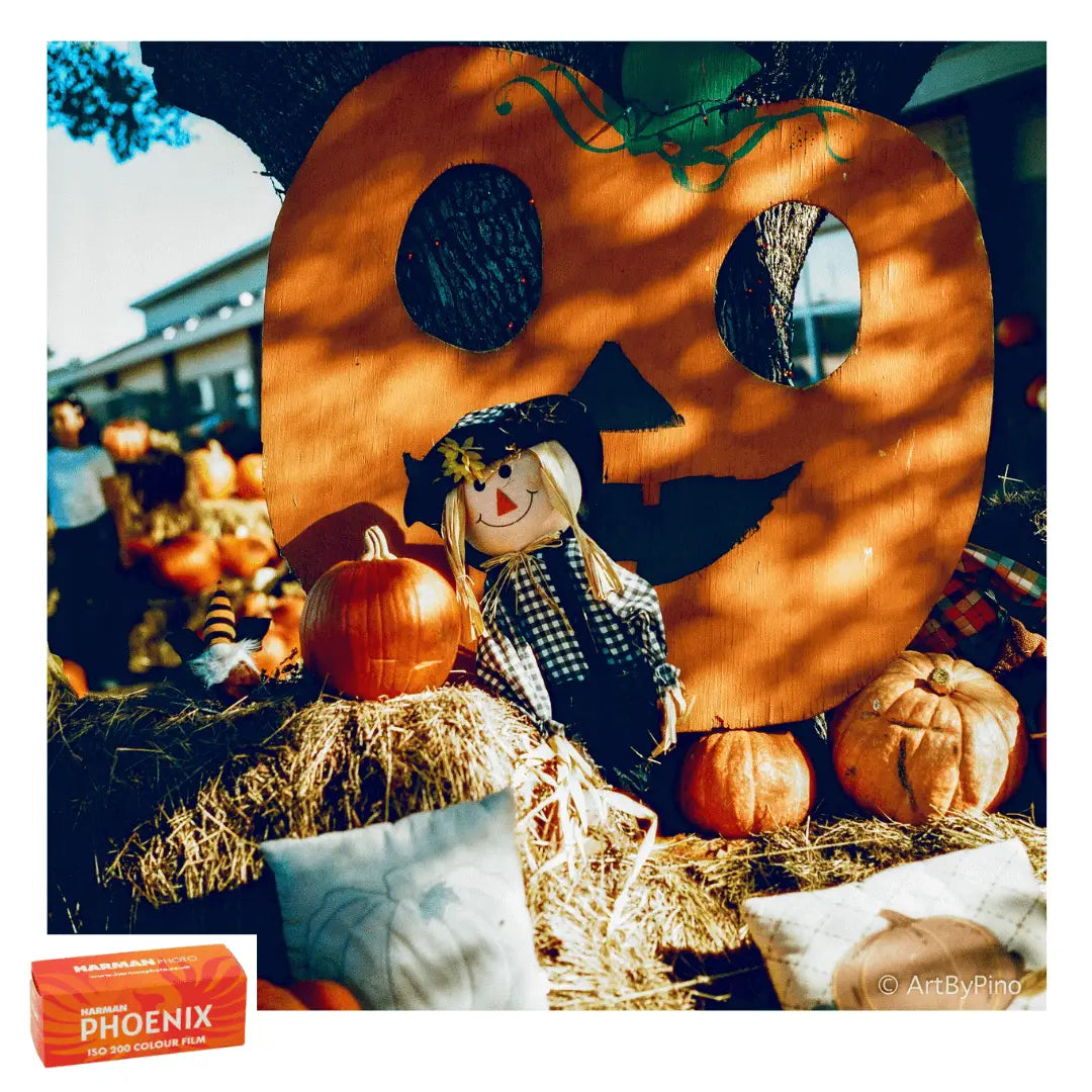 A rustic, orange-painted wooden pumpkin cutout with carved eyes and a smiling mouth.