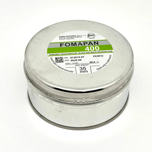 A cylindrical silver metal canister containing fomapan 400 black and white negative film, labeled with green and gray branding.