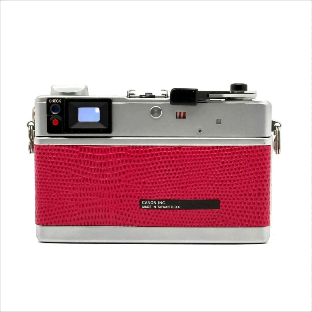 A vibrant red crocodile-textured canon ae-1 film camera with a silver top plate and black label.