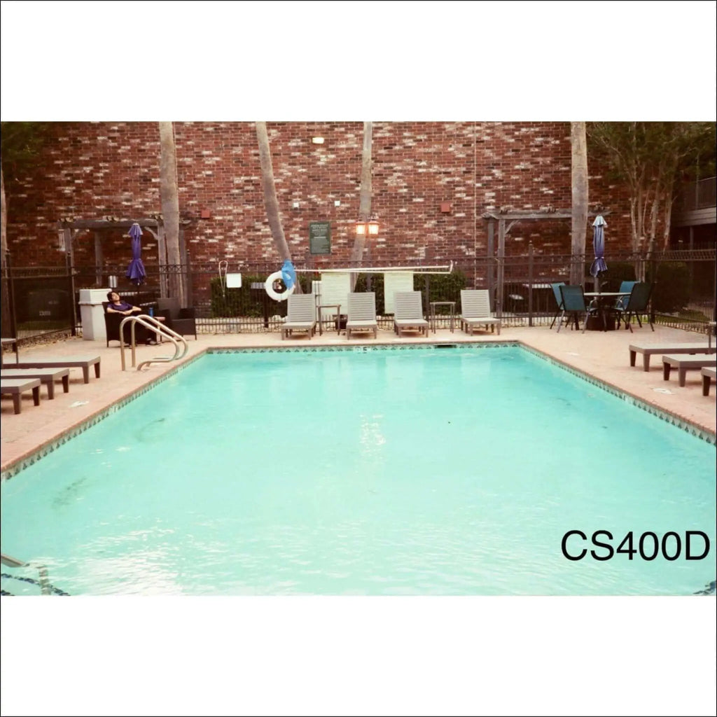 Rectangular in shape with clear turquoise water and tiled edges, surrounded by lounge chairs and a brick wall