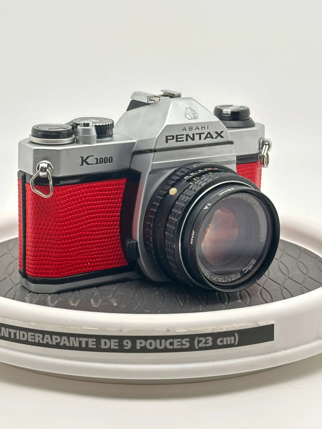 Silver and red asahi pentax k1000 film camera with textured leather grip.