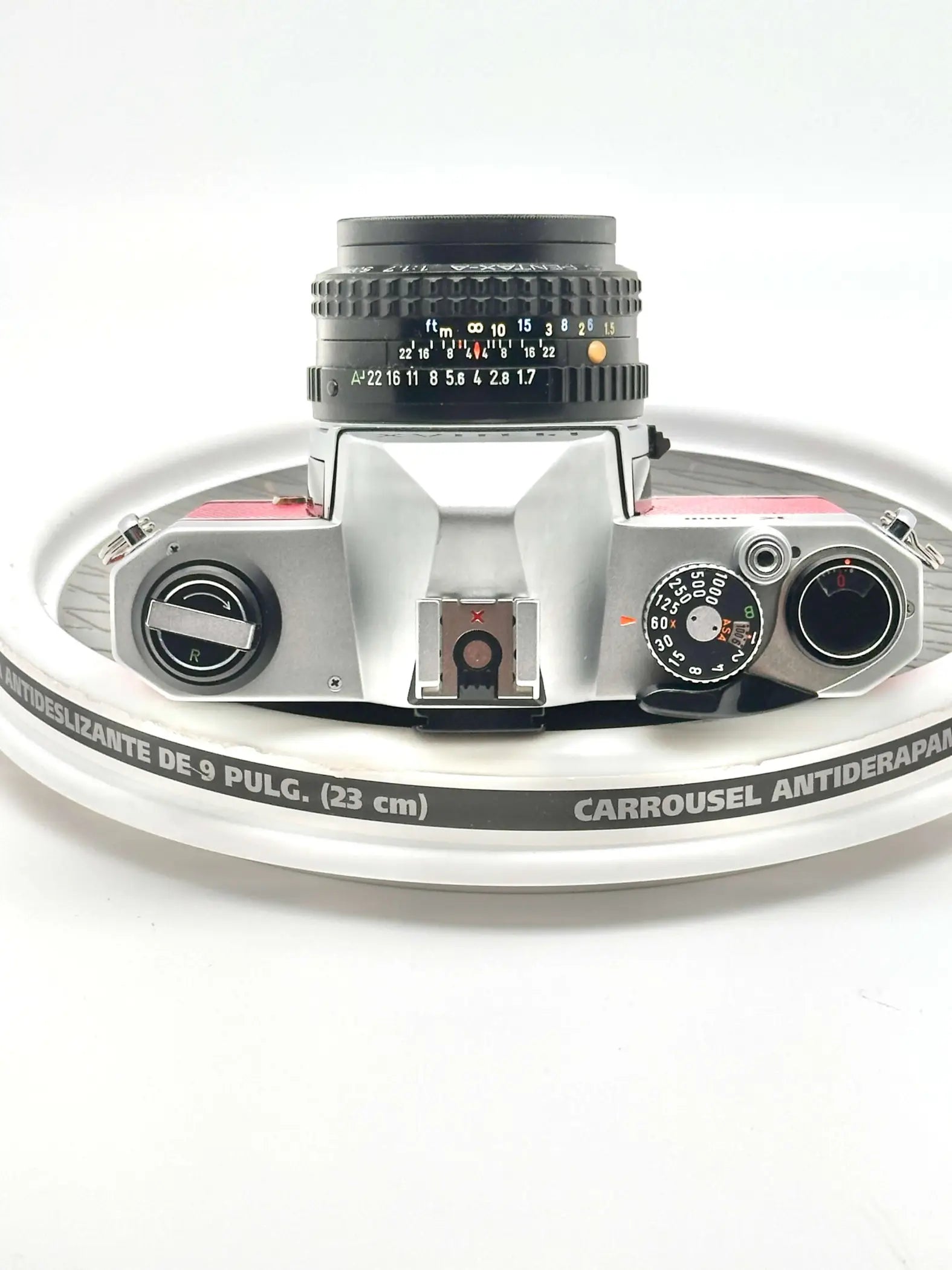 Silver and pink vintage film camera with a black lens, featuring manual focus rings and dials.