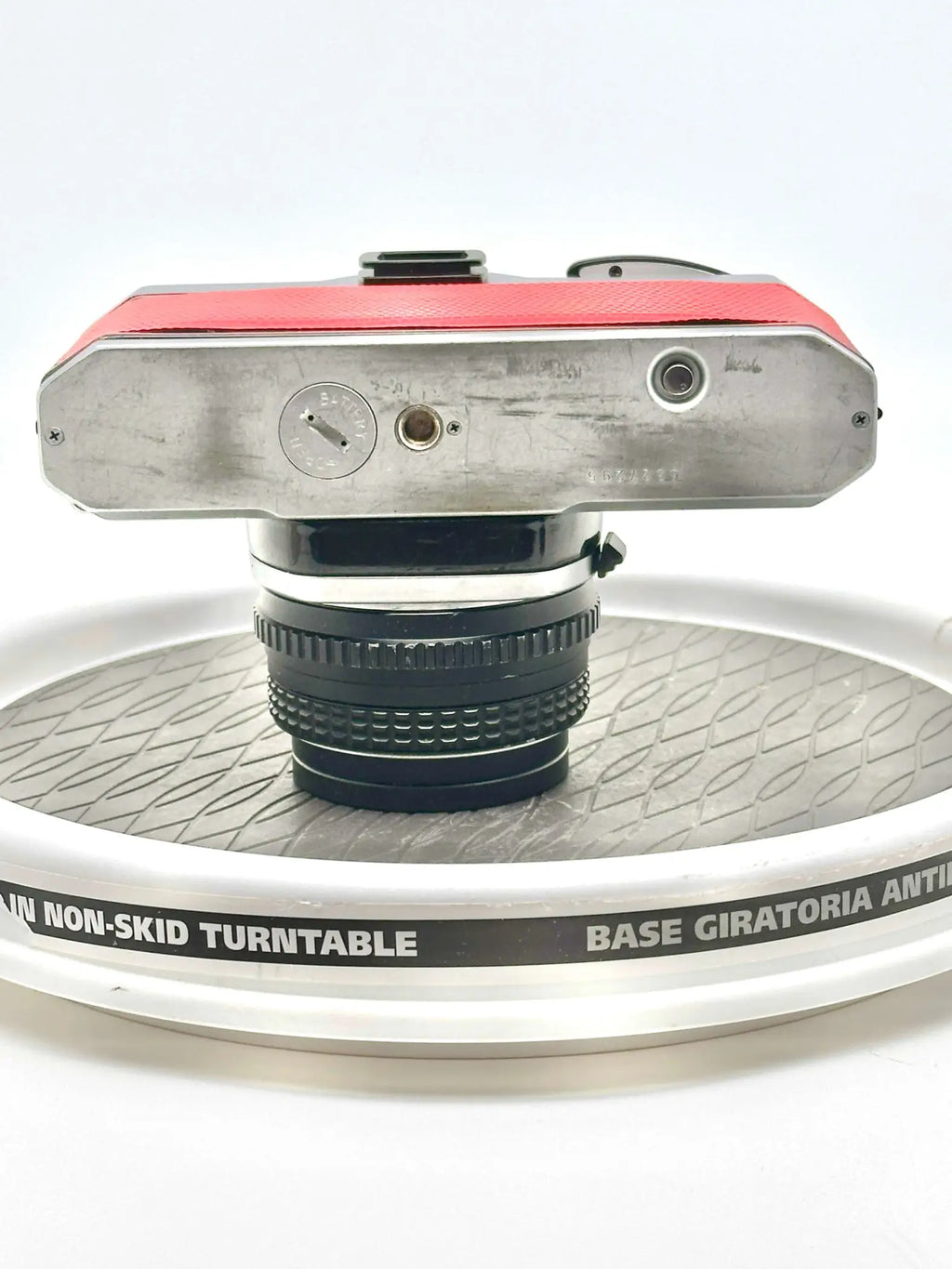 Red and silver vintage camera with a black lens mounted on top.