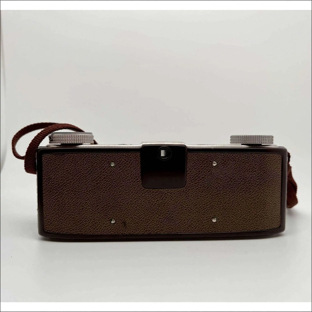Brown textured leather-bodied vintage camera with silver metal dials and a matching brown strap.