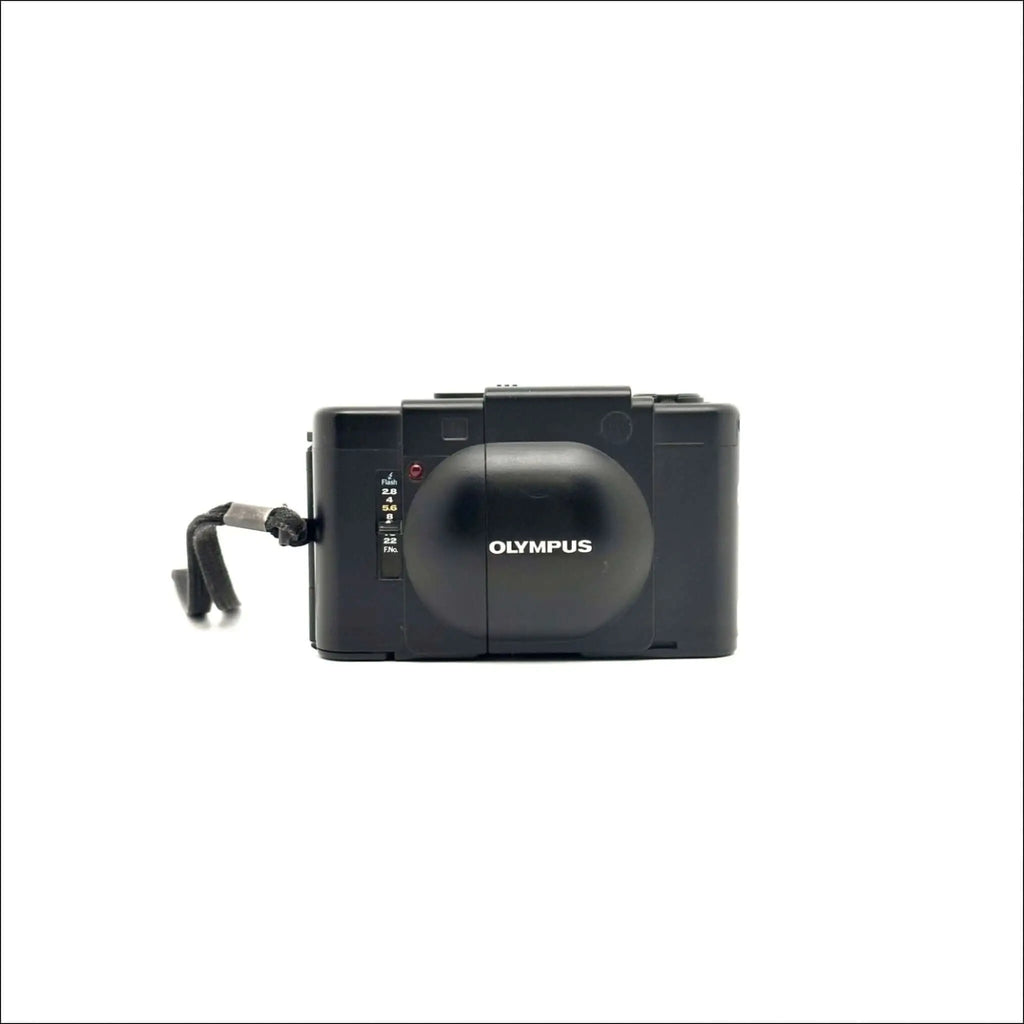 Black olympus digital camera with a rounded lens cover and a textured grip.