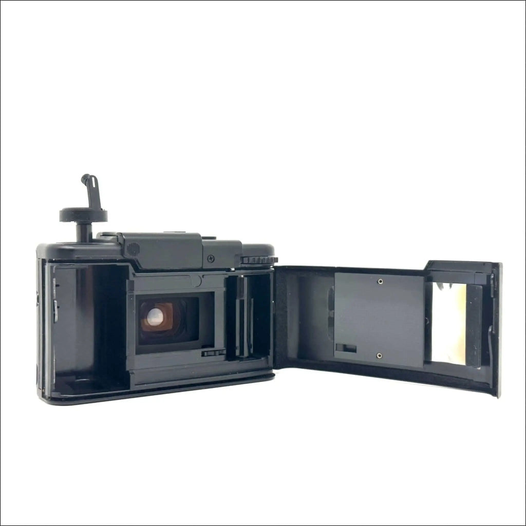 Black plastic instant camera with hinged back open to reveal the film chamber and viewfinder.