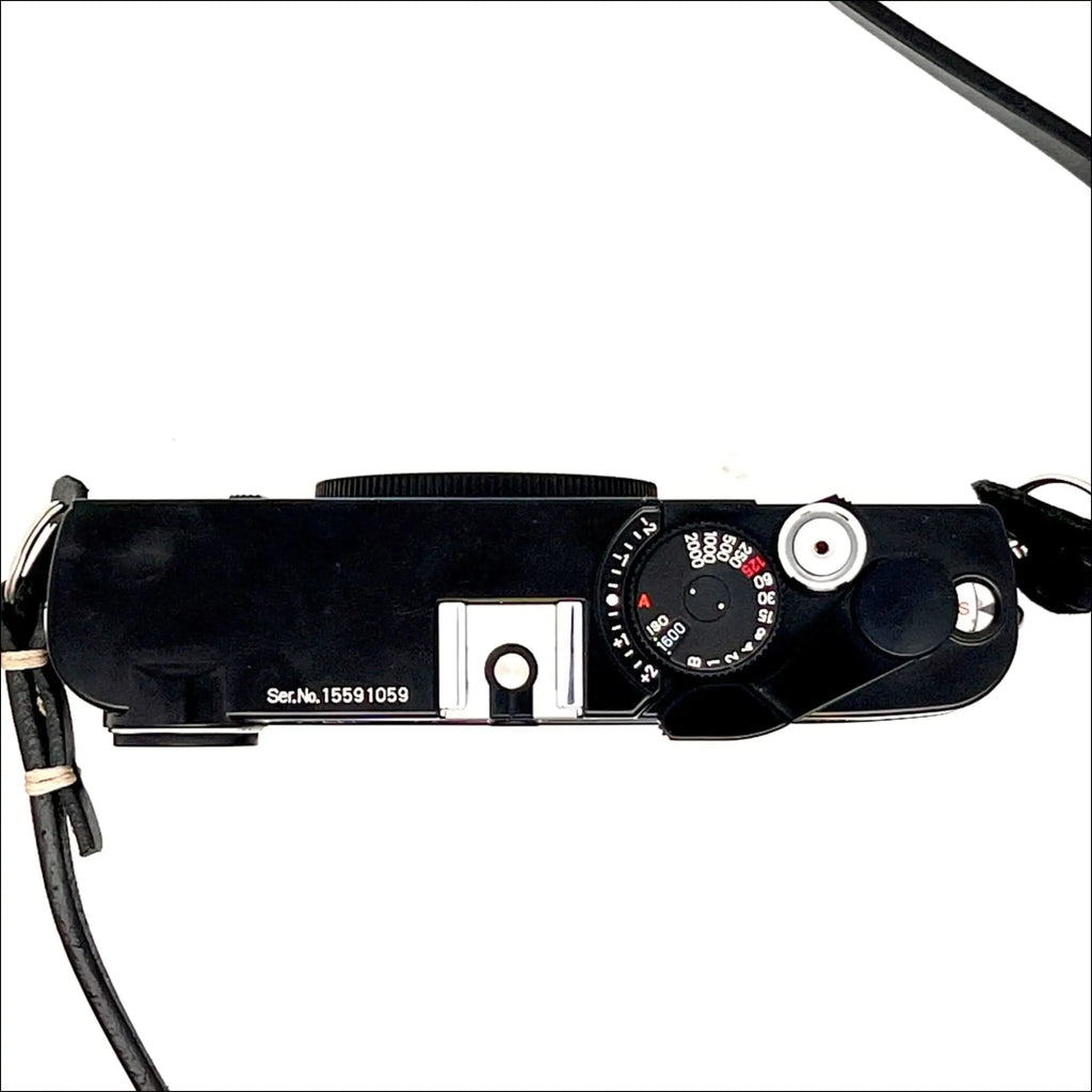 Black leica m10 film camera with a silver shutter speed dial and black leather strap.